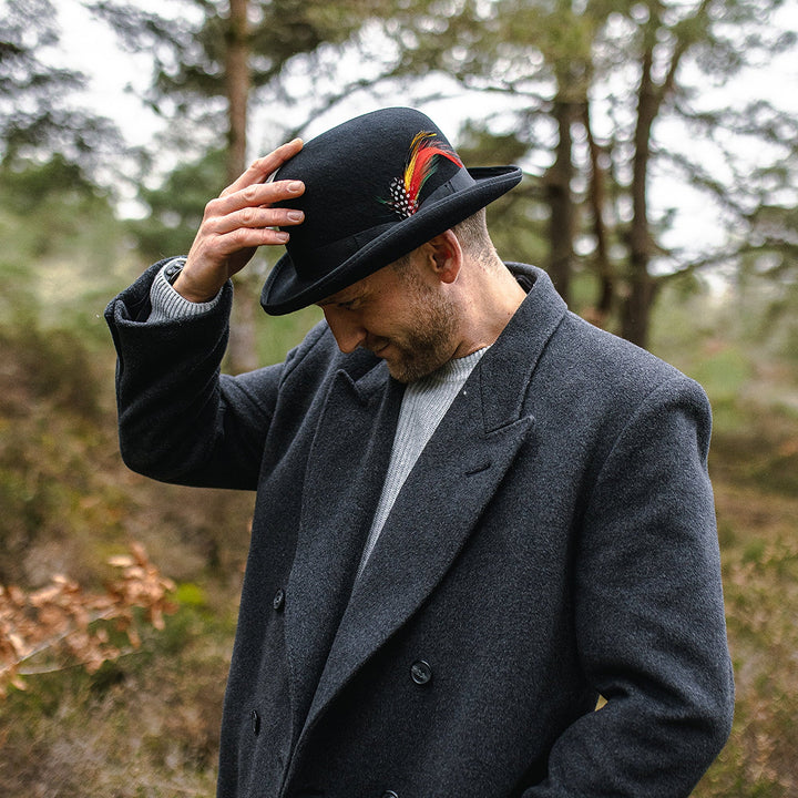 Black bowler hat with curved brim, grosgrain band and feather detail