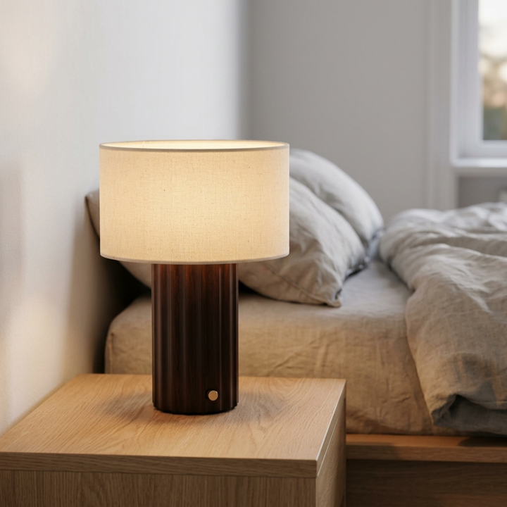 Dark brown table lamp with a cream drum shade on a bedside table