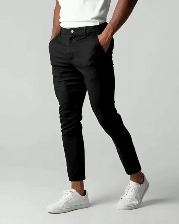 Men's slim tapered chino trousers shown in black and navy with button waist and ankle-length legs