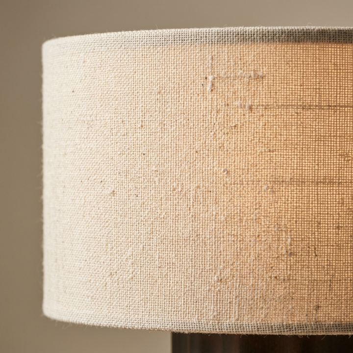 Dark brown table lamp with a cream drum shade on a bedside table