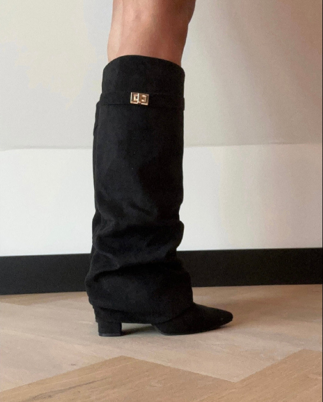 Women's black knee-high boots with slouchy shaft and gold buckle trim at calf