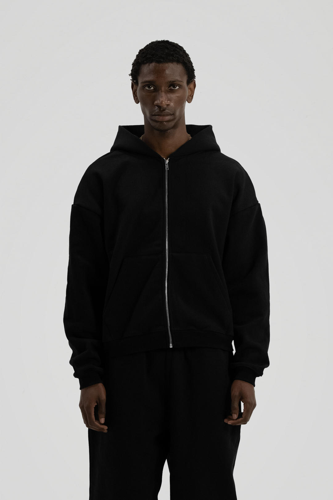 Man wearing a black full-zip hooded sweatshirt with a kangaroo pocket