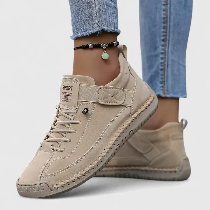Orthopedic sneakers with white upper and beige sole, worn with jeans