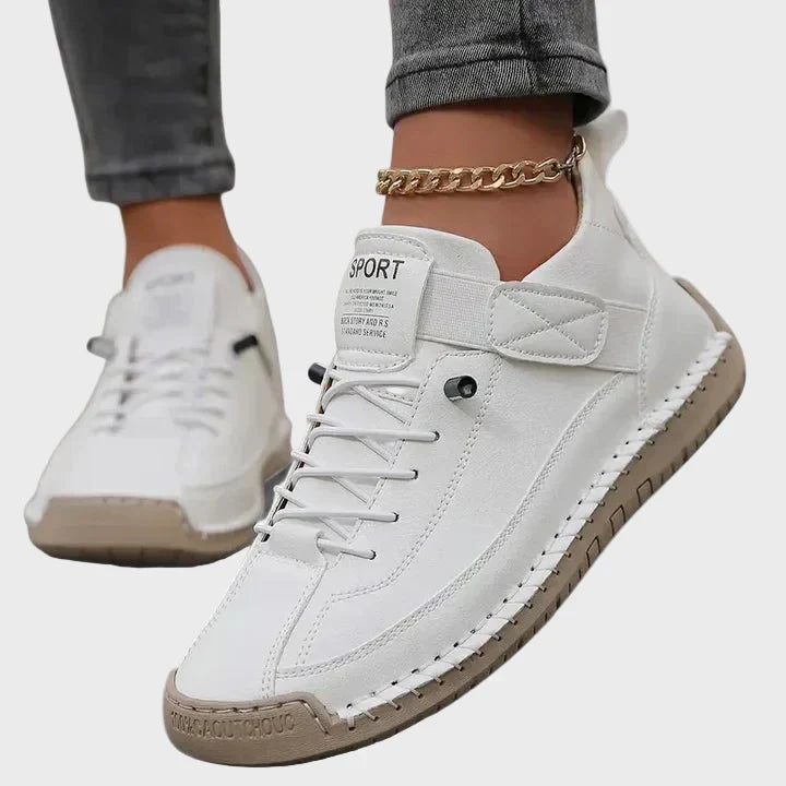 Orthopedic sneakers with white upper and beige sole, worn with jeans