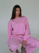 Women's pink cropped crewneck sweatshirt with long sleeves and white chest logo