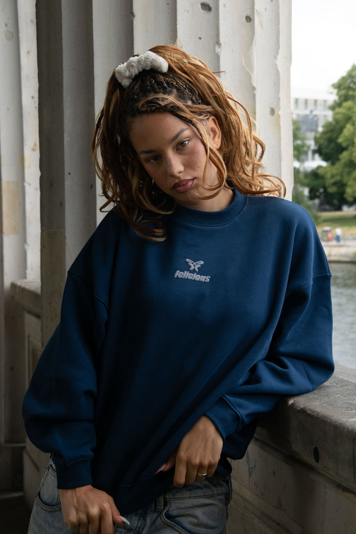 Women's navy crewneck sweatshirt with raised chest logo and ribbed trims