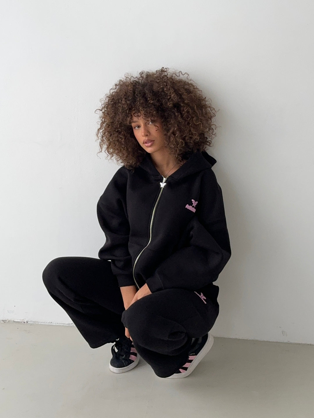 Black women's zip-up hoodie with hood, front pockets and pink chest logo