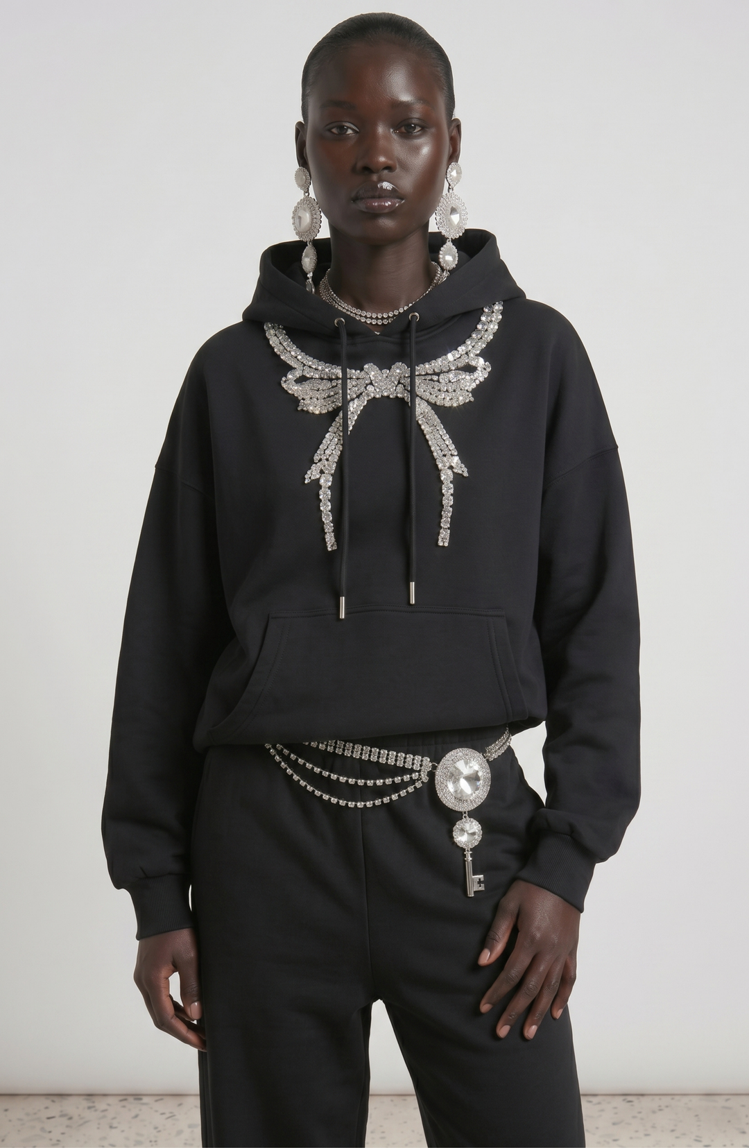 Black pullover hoodie with embellished wing detail, hood, drawstrings and front pouch pocket