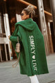 Woman wearing a longline hooded knit cardigan with graphic back lettering