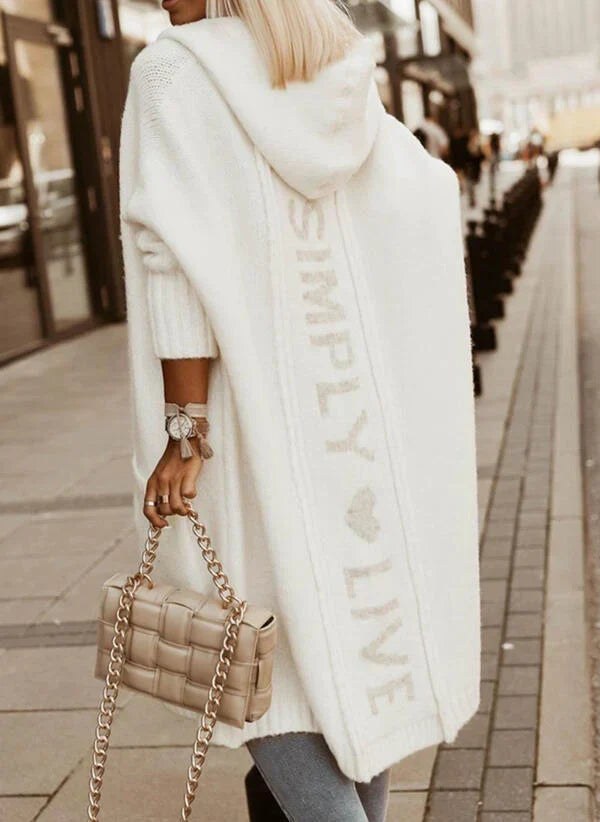Woman wearing a longline hooded knit cardigan with graphic back lettering