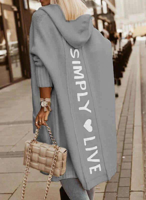 Woman wearing a longline hooded knit cardigan with graphic back lettering