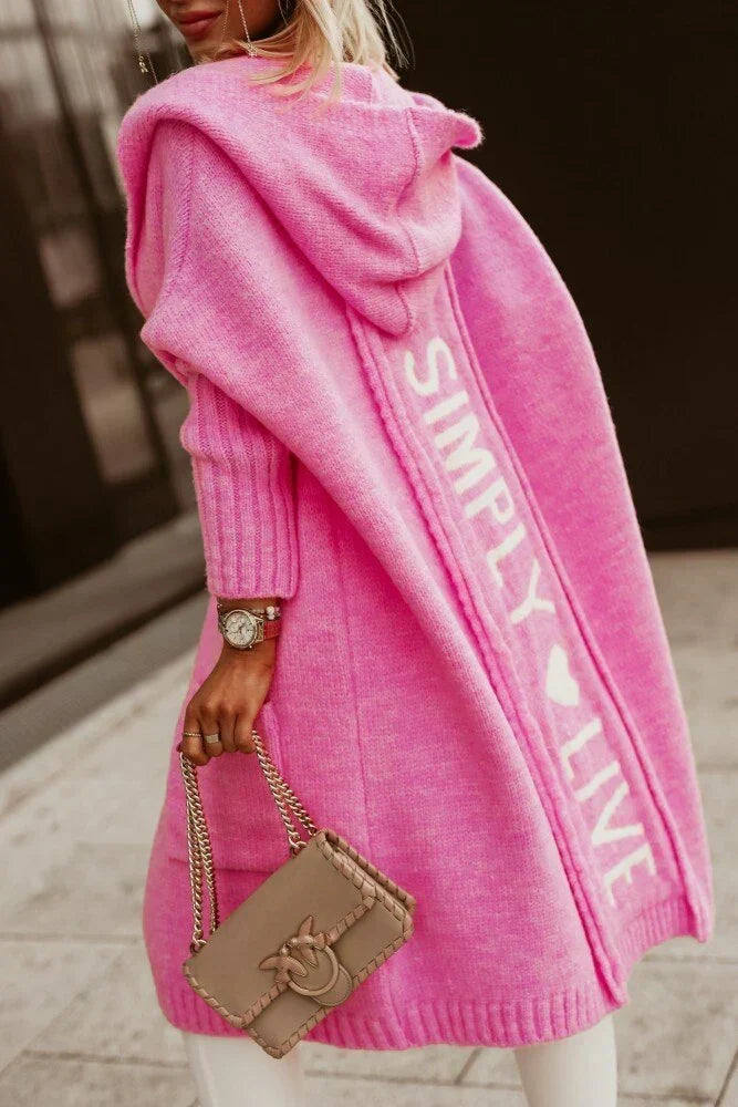 Woman wearing a longline hooded knit cardigan with graphic back lettering