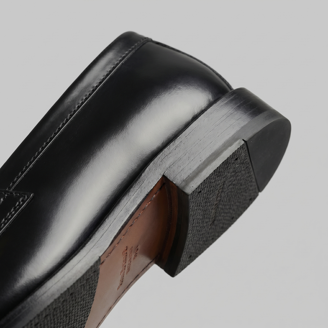 Men's black penny loafers with glossy finish, almond toe and low heel
