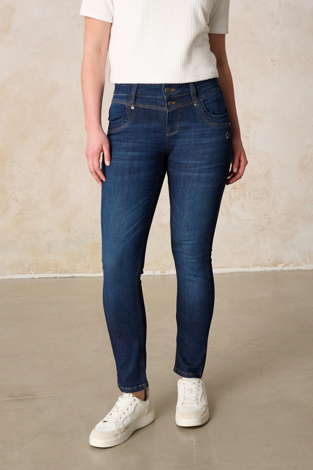 Women's dark blue slim fit jeans with mid-rise button fly and five pockets