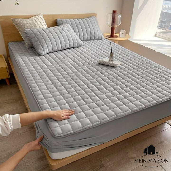 Quilted mattress topper with a padded square pattern on a bed
