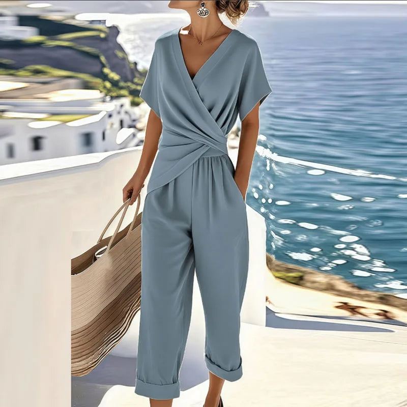 Women's wrap top and cropped trousers set in neutral tone, styled on a terrace overlooking the ocean