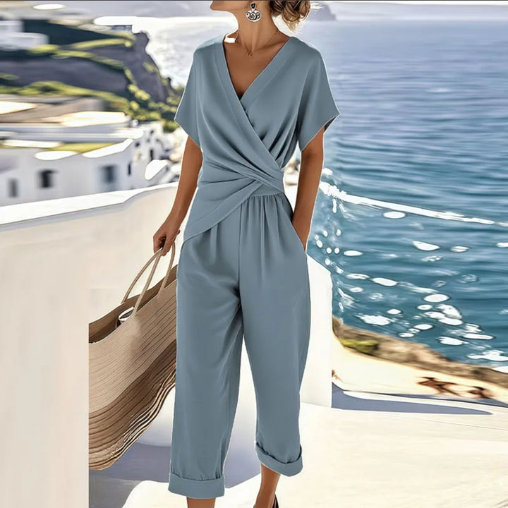 Women's wrap top and cropped trousers set in neutral tone, styled on a terrace overlooking the ocean