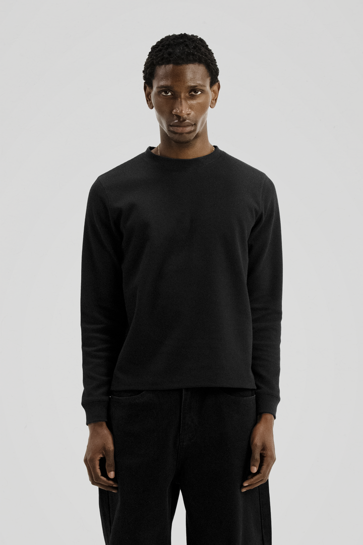 Black long sleeve crew neck top with ribbed cuffs and hem