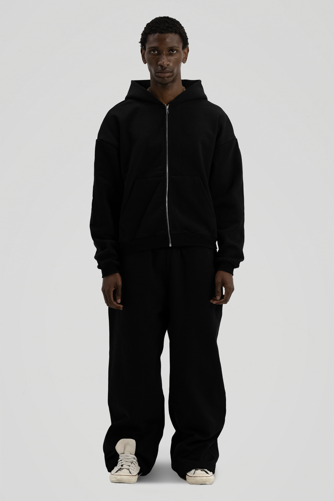 Man wearing a black full-zip hooded sweatshirt with a kangaroo pocket