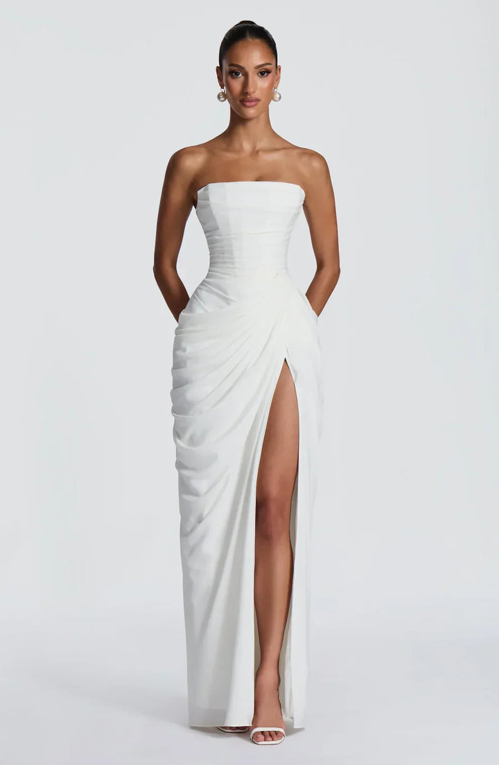 Woman wearing strapless ruched maxi dress with high side slit in yellow and navy versions