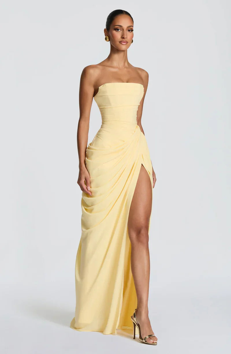 Woman wearing strapless ruched maxi dress with high side slit in yellow and navy versions