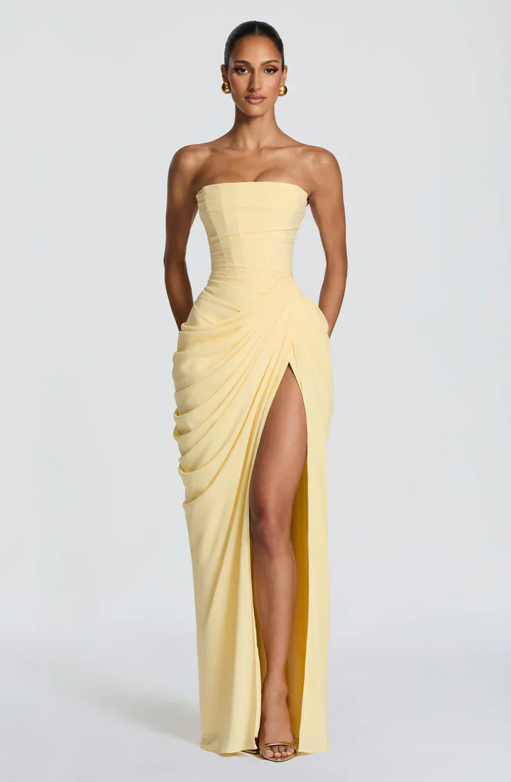 Woman wearing strapless ruched maxi dress with high side slit in yellow and navy versions