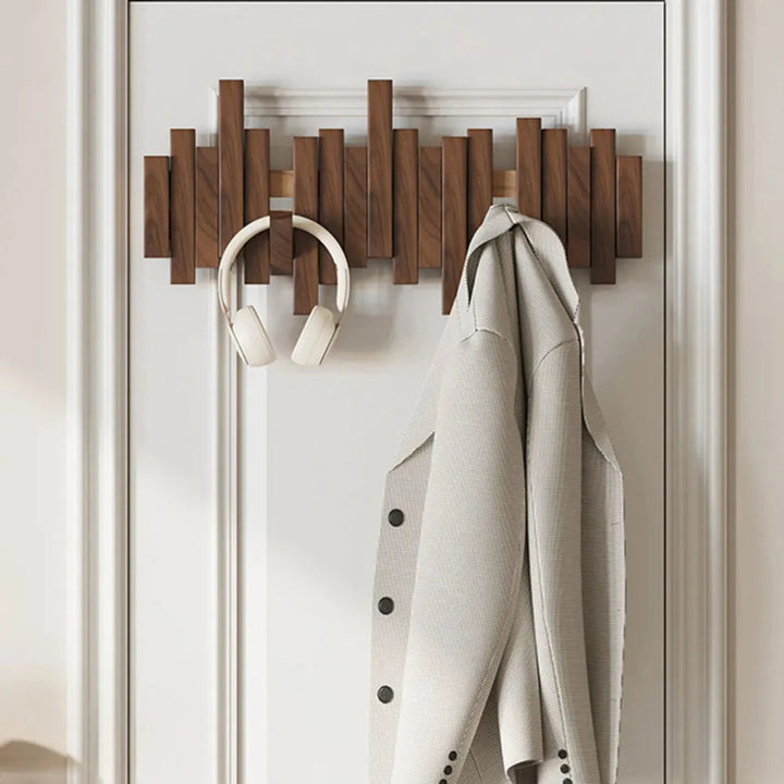 Wall-mounted wooden coat rack with staggered piano-style slats and angled hooks