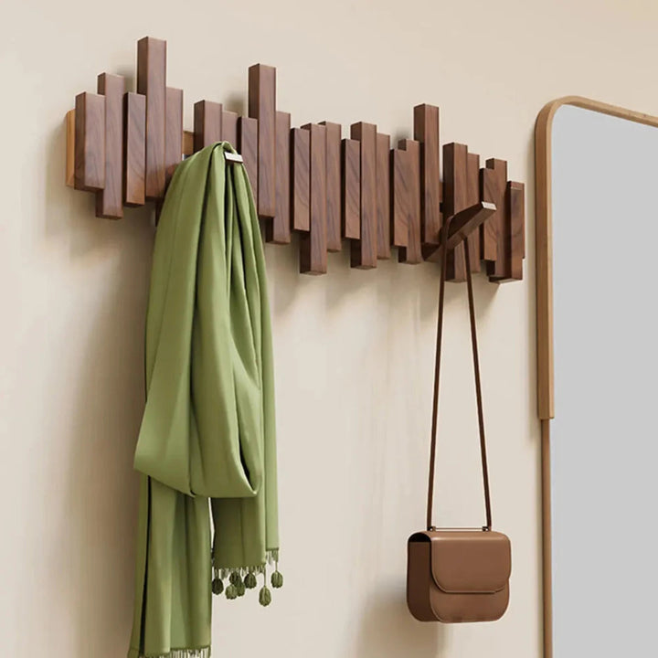 Wall-mounted wooden coat rack with staggered piano-style slats and angled hooks