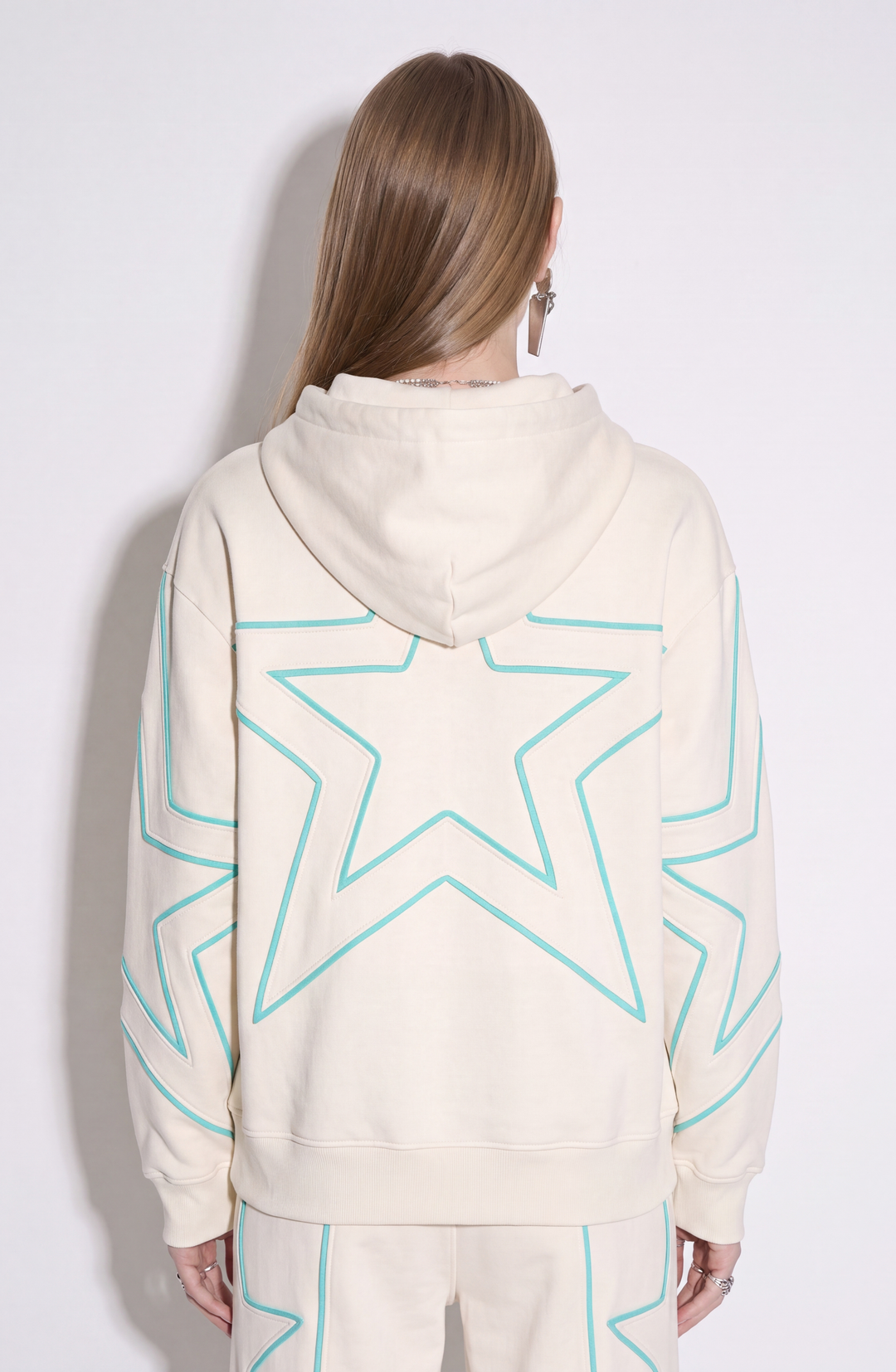 Cream hoodie with turquoise outlined star detailing, drawstring hood and kangaroo pocket