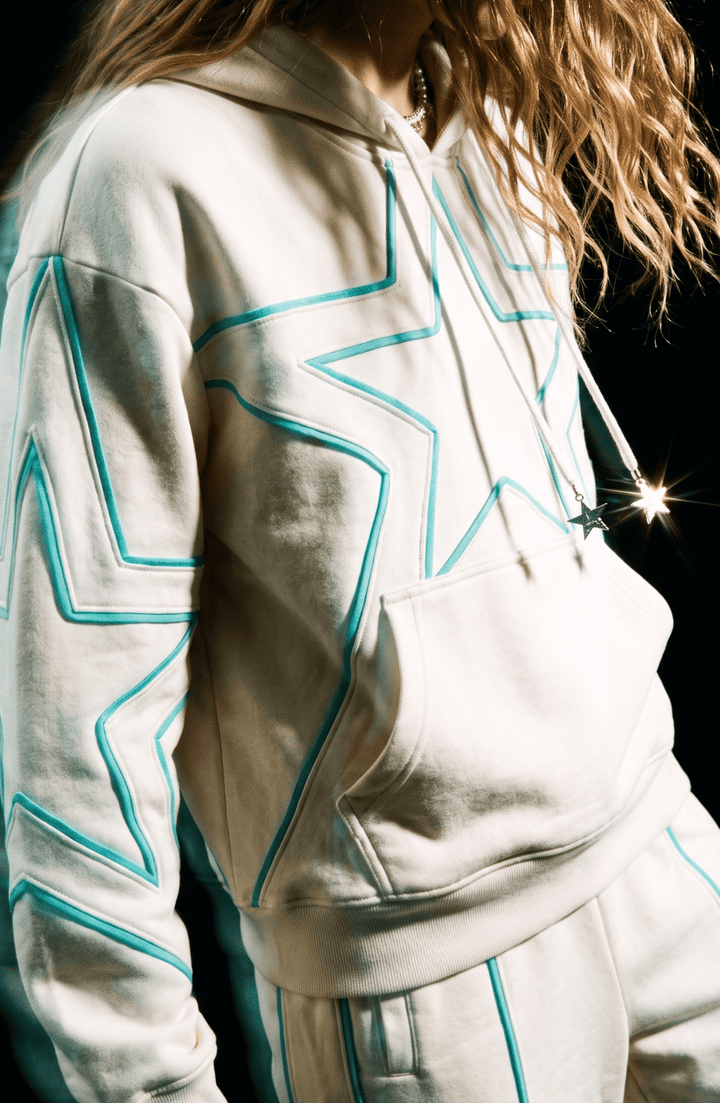 Cream hoodie with turquoise outlined star detailing, drawstring hood and kangaroo pocket