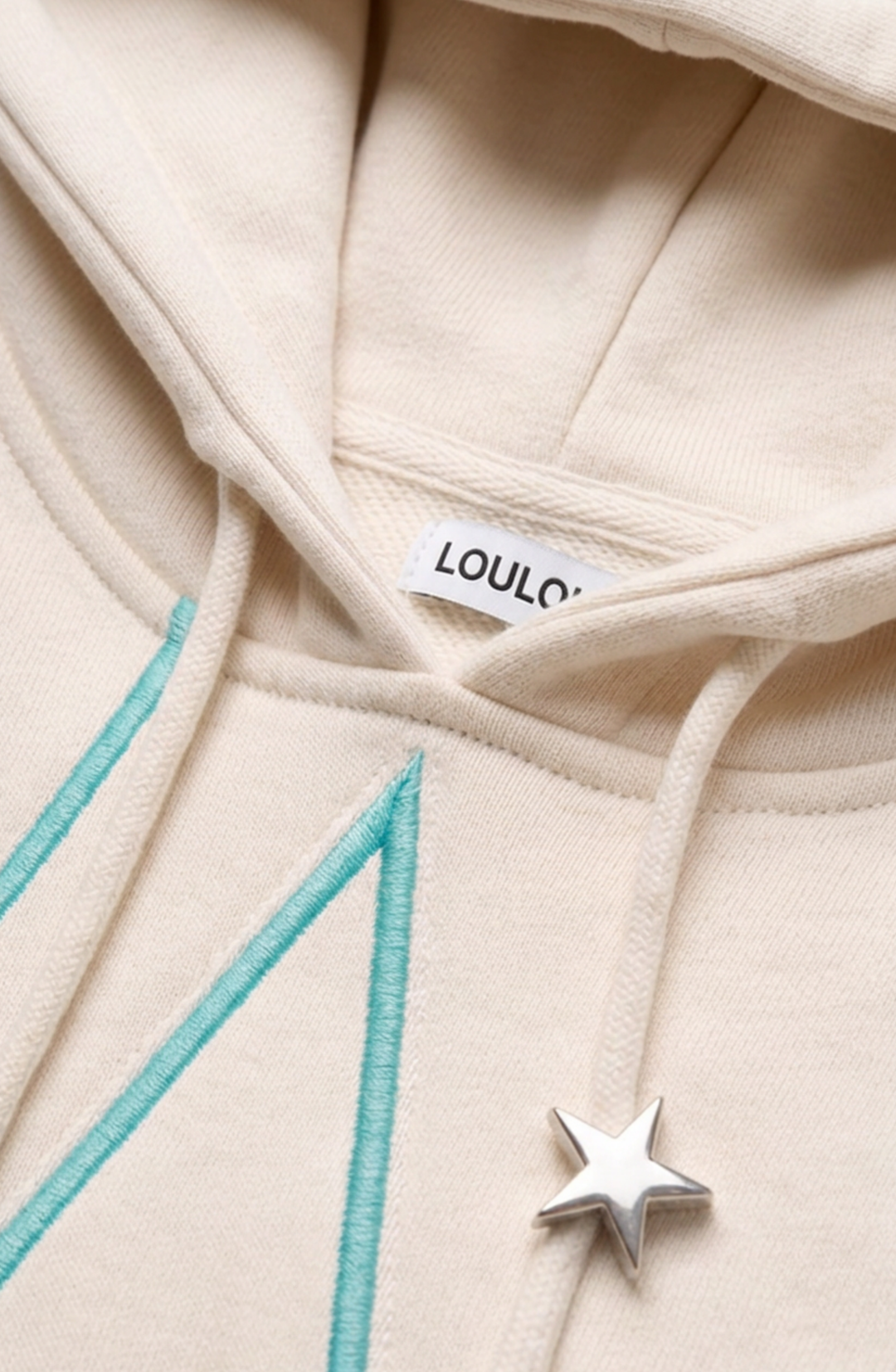 Cream hoodie with turquoise outlined star detailing, drawstring hood and kangaroo pocket