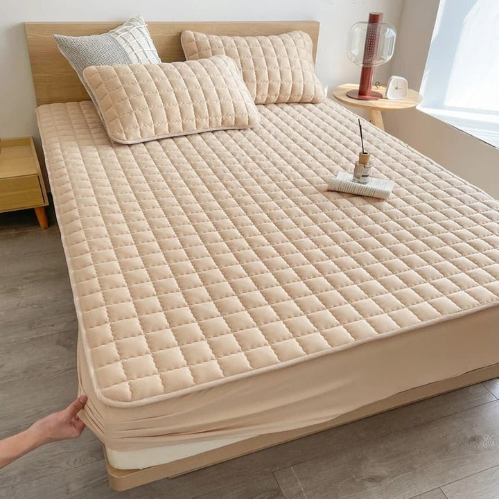 Quilted mattress topper with a padded square pattern on a bed