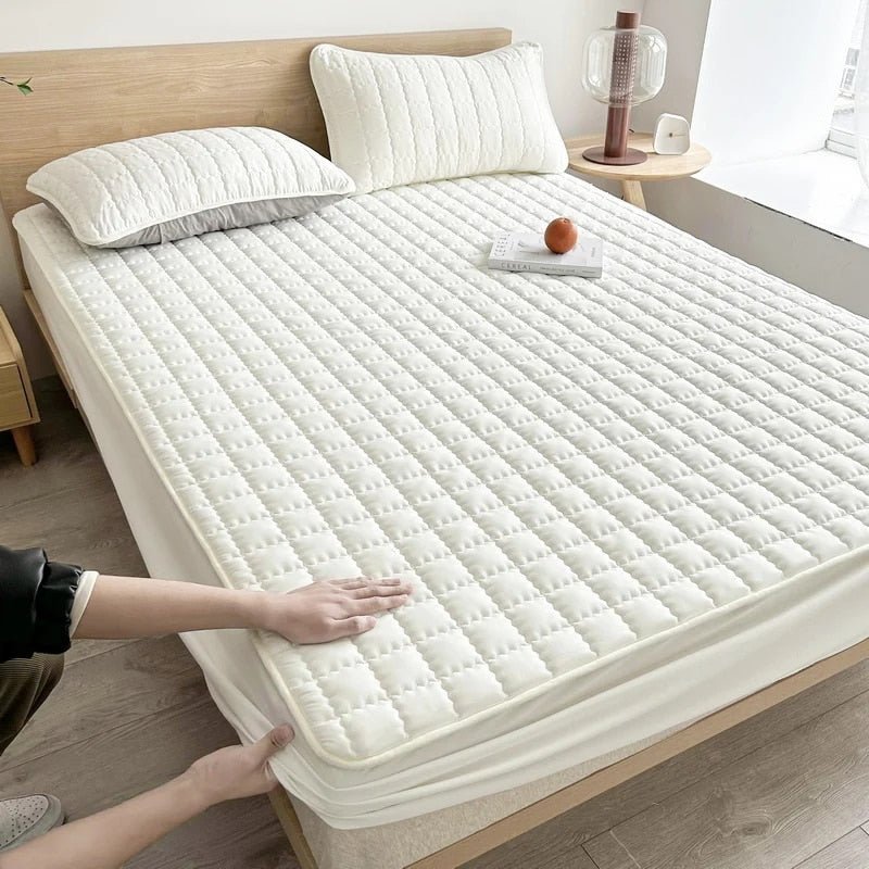 Quilted mattress topper with a padded square pattern on a bed