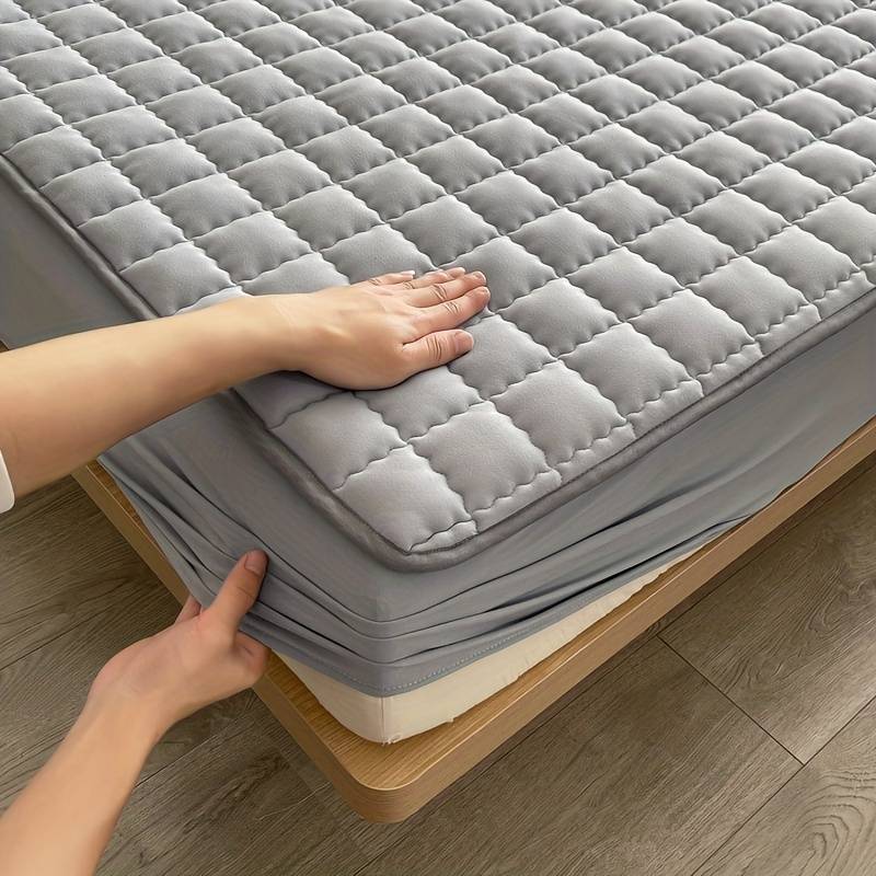 Quilted mattress topper with a padded square pattern on a bed