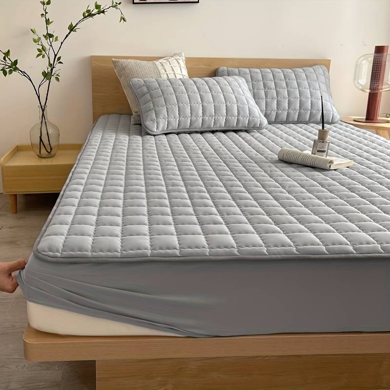 Quilted mattress topper with a padded square pattern on a bed