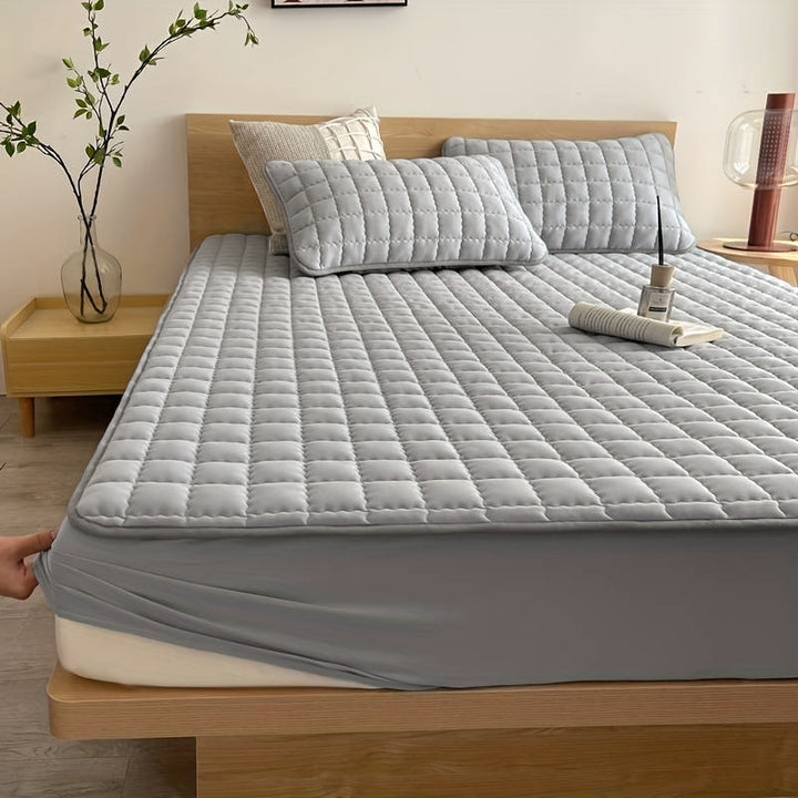 Quilted mattress topper with a padded square pattern on a bed
