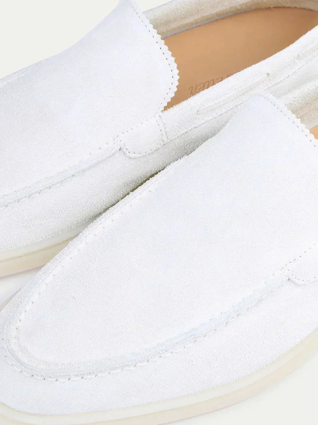Men's white moc toe slip-on loafers with stitched detailing and flat soles