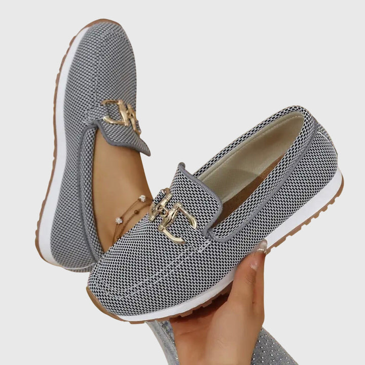 Women's textured knit loafers with gold buckle detail and cushioned sole, shown in blue and beige.